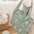 Un mini sac à langer élégant, posé sur une table avec des accessoires pour bébé à l'intérieur.